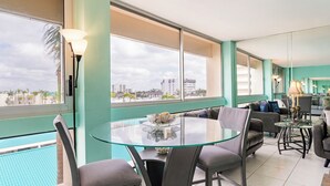 Una sala de estar moderna con una mesa de vidrio, sofás grises y vista a una piscina.