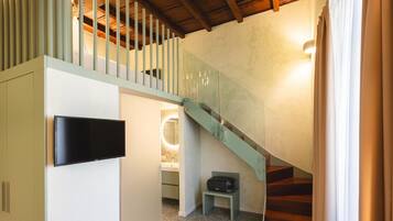 A modern interior with a staircase, a flat-screen TV, and a small seating area.