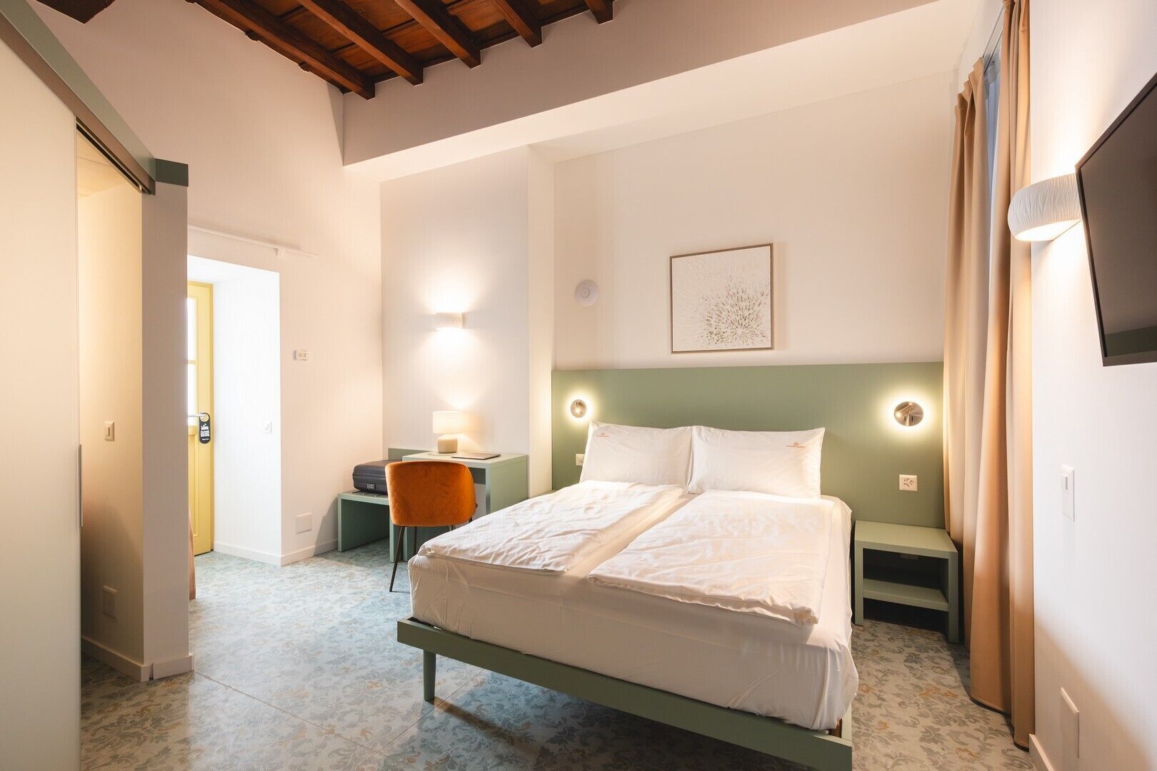 A bedroom with a bed, bedside lamps, a desk, and a chair.