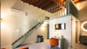A modern interior with a glass staircase, a desk with a chair, a flat-screen TV, and a bathroom with a mirror. - Palazzo Canetti Locarno (Locarno)