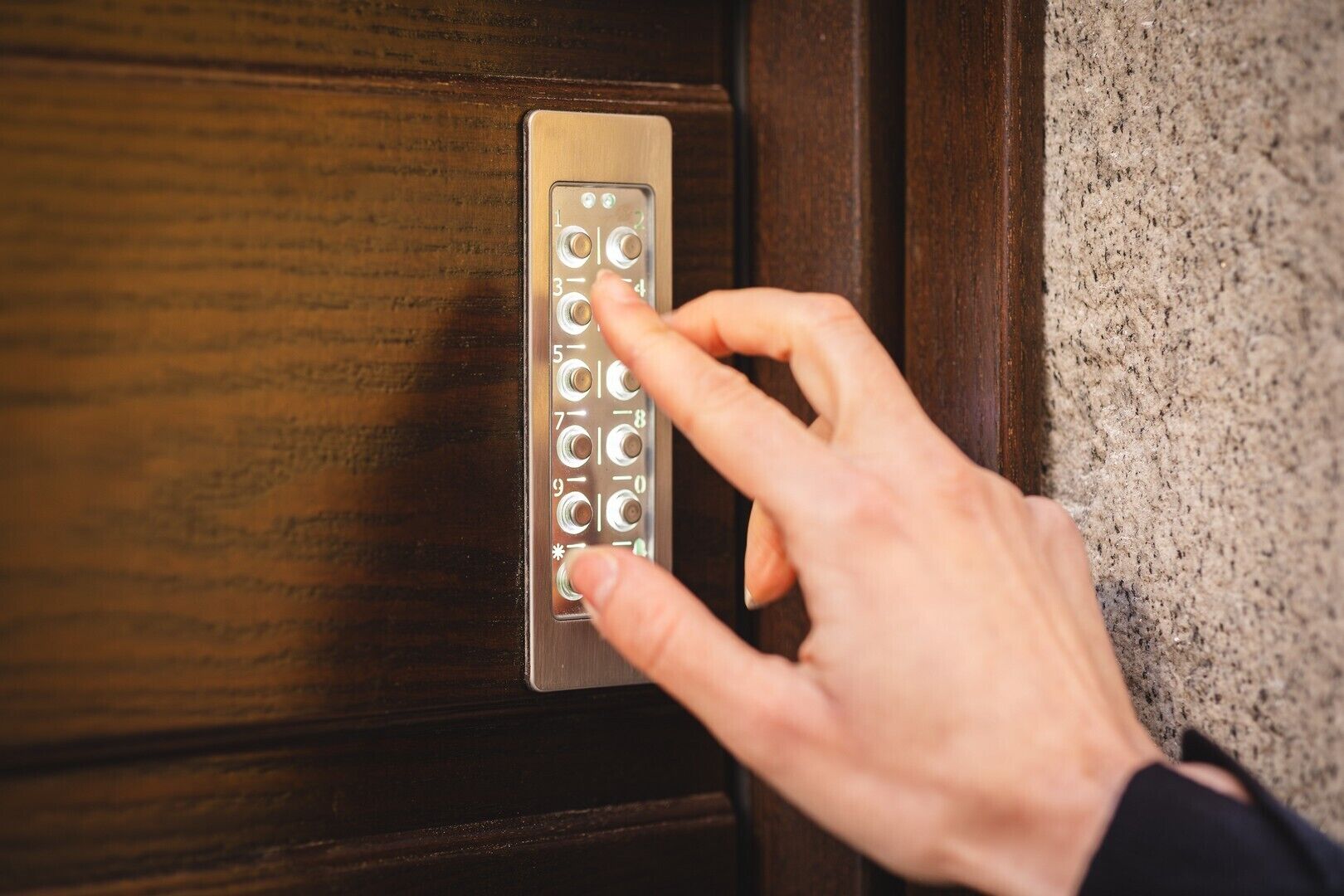 Eine Hand drückt eine Tastatur an einer Holztür.