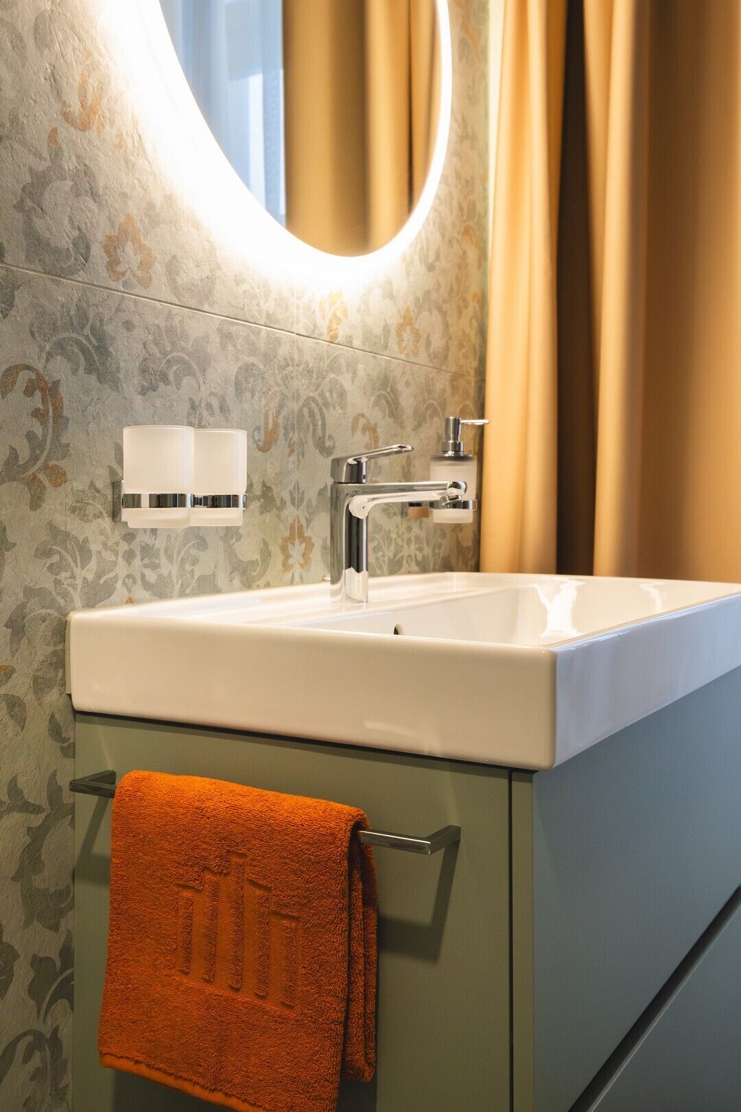 A bathroom with a white sink, a mirror, and a towel rack.