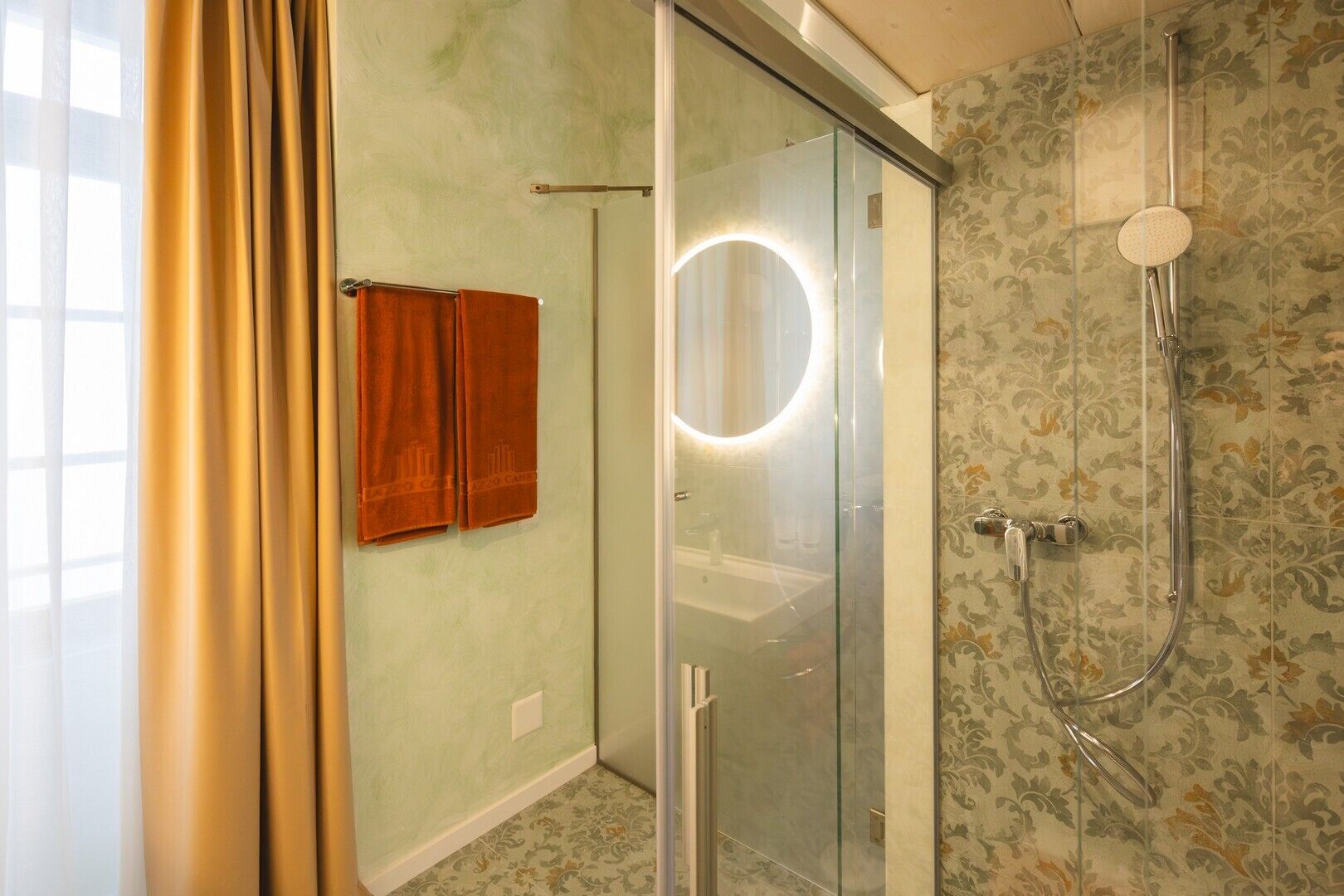 A bathroom with a glass shower enclosure, a round mirror, and a showerhead.
