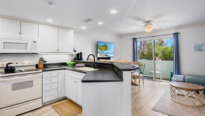 A modern kitchen with white cabinets, a microwave, stove, and a large island with a sink.
