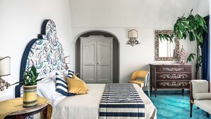 Un dormitorio con cama, cómoda, silla, planta en maceta y puerta con arco.