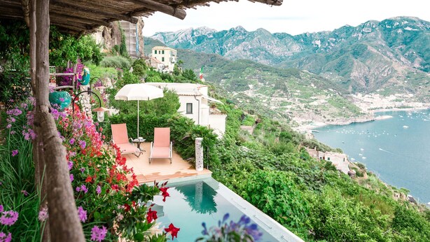 Zona junto a la piscina con vista al mar y a las montañas.