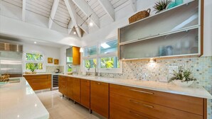 Una cocina moderna con armarios de madera, encimera blanca y salpicadero con mosaicos.