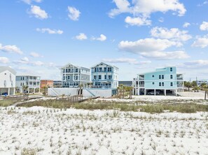 A beachfront property with multiple-story buildings, a sandy beach, and a clear sky. - Gulf Views! Private Pool Overlooking the Gulf! Elevator! (Mexico Beach)