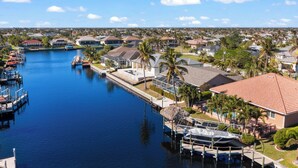 A marina with boats docked, a swimming pool, and houses with a red roof.