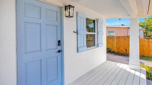A house with a blue door, a window with shutters, and a porch.