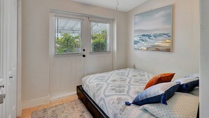 A bedroom with a bed, a ceiling fan, a window with blinds, and a painting on the wall.