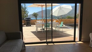 A room with a sliding glass door leading to an outdoor patio with a table, chairs, and a grill.