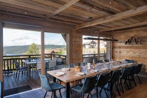 A dining area with a table set for six, large windows, and a view of the outdoors. - ✨ Le Refuge des 3 Oursons – 14 p. - with Swim Spa, Sauna (Gérardmer)
