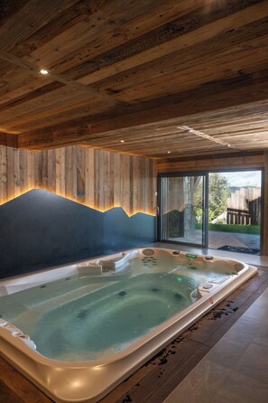 Ein Whirlpool in einem Raum mit Holzbalkendecke und Blick ins Freie.