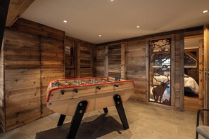 Ein Zimmer mit Tischfußball, Holzwänden und einer Hirschskulptur.