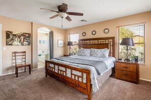 Cozy bedroom with a central bed, ceiling fan, and wooden nightstand.
