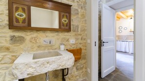 A stone wall bathroom with a marble sink, wooden cabinet, and a door leading to another room. - Casa degli Archi, Sicilian apartment with small terrace - Modica (Modica)