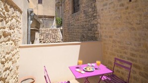 A narrow courtyard with stone walls, a tiled roof, and a table with chairs. - Casa degli Archi, Sicilian apartment with small terrace - Modica (Modica)