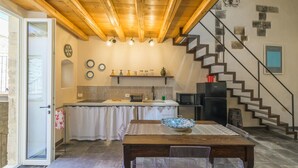 A kitchen with a wooden ceiling, a dining table with chairs, a staircase, and a refrigerator. - Casa degli Archi, Sicilian apartment with small terrace - Modica (Modica)