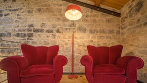 Two red armchairs facing each other with a stone wall and a wooden ceiling in the background. - Casa degli Archi, Sicilian apartment with small terrace - Modica (Modica)