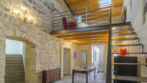 A spacious room with a stone wall, a wooden ceiling, a staircase, and a dining area with a table and chairs. - Casa degli Archi, Sicilian apartment with small terrace - Modica (Modica)