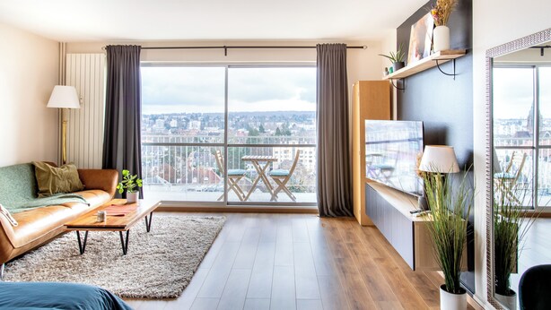 Una sala de estar moderna con un ventanal grande, un sofá, una mesa de centro y un televisor.
