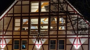 A traditional building with a tiled roof and multiple windows, featuring a central chandelier and illuminated signage. - Hotel Pflug (Dornhan)