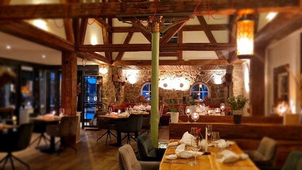 A restaurant with wooden beams, stone walls, and tables set for dining. - Hotel Pflug (Dornhan)