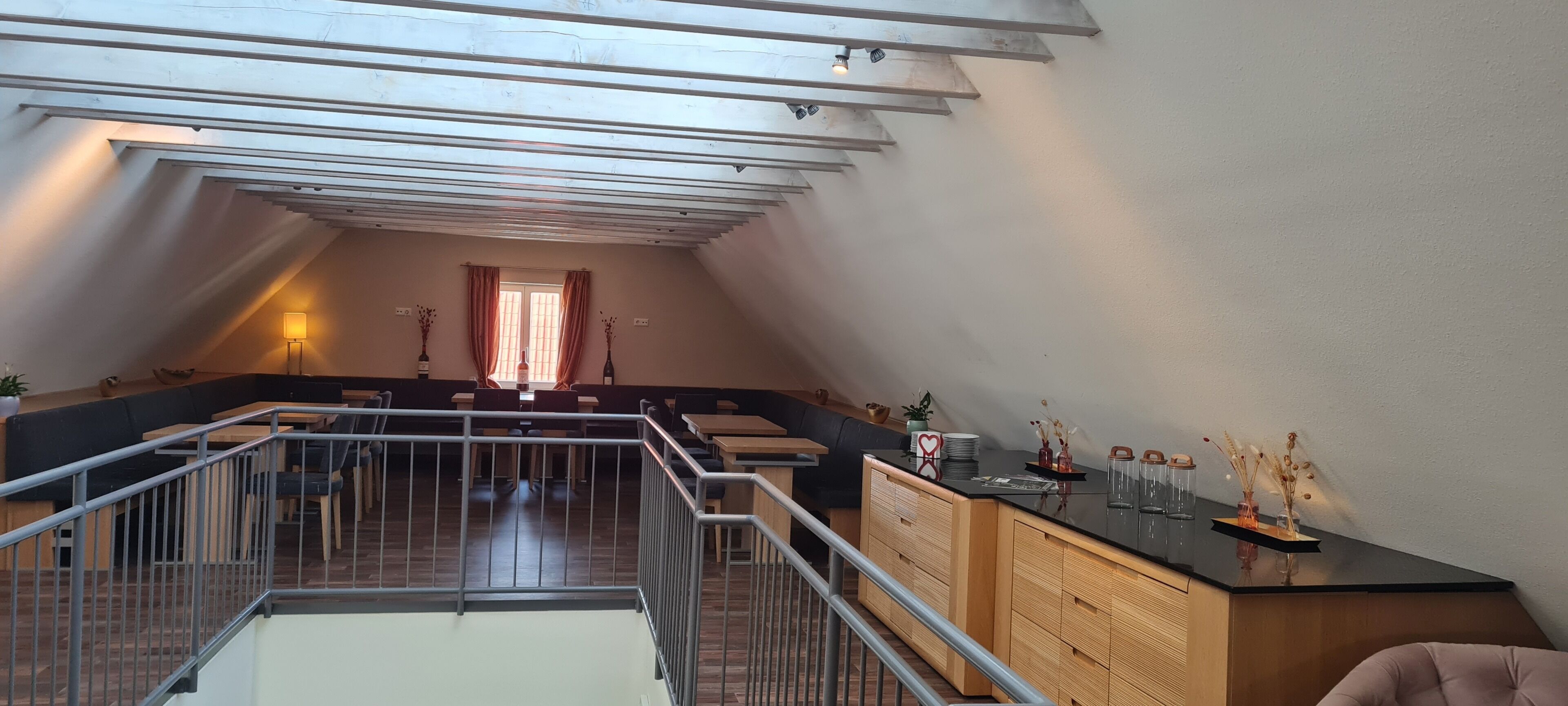 Un loft spacieux avec de hauts plafonds, une mezzanine avec une rambarde, un coin repas et une vue sur l’extérieur.