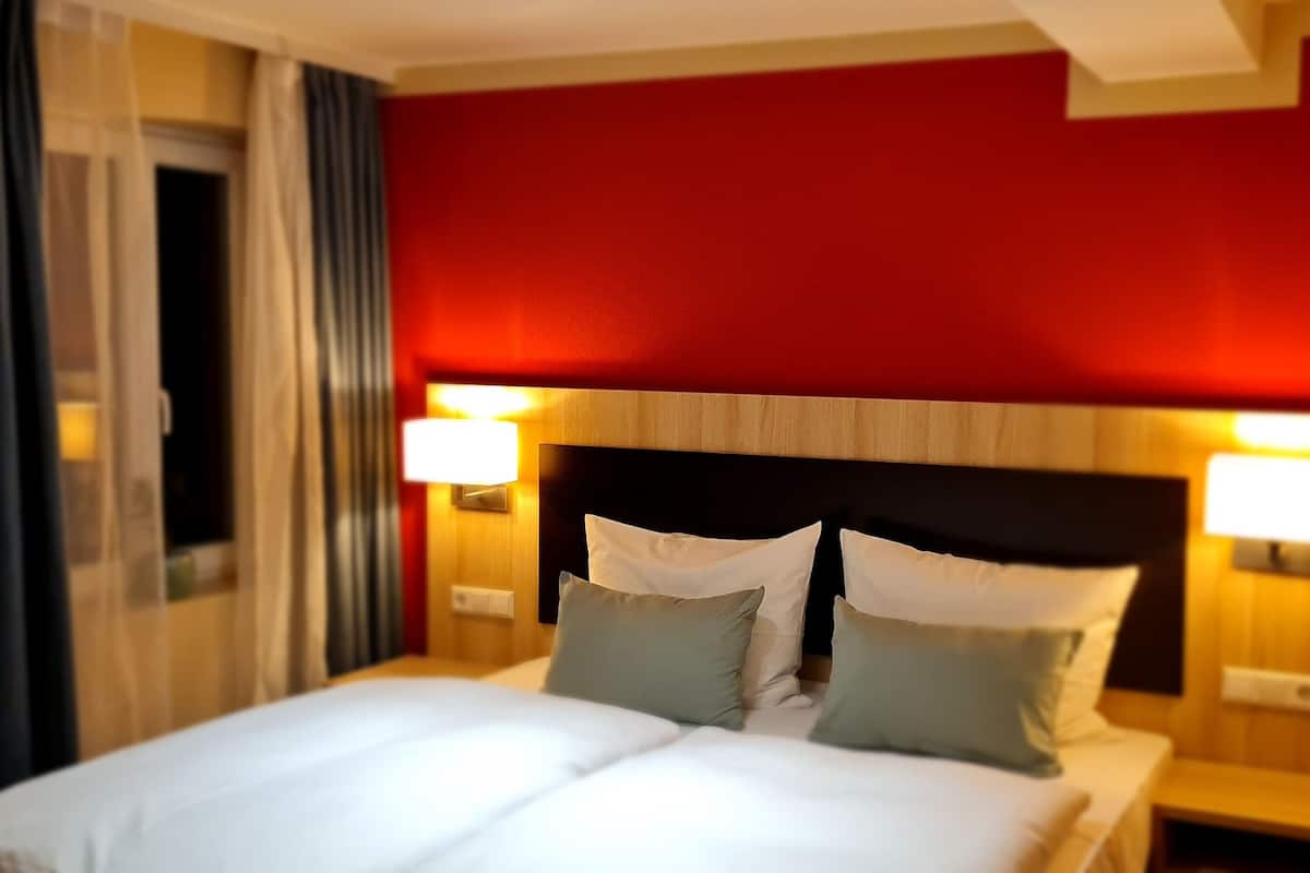 A hotel room with a bed, two bedside tables, and a nightstand.