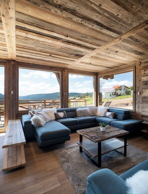 A spacious living area with a large sectional sofa, a wooden coffee table, and a view of the outdoors.