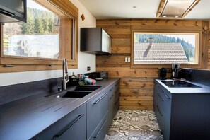 Eine moderne Küche mit großem Fenster, Holzvertäfelung und Fliesenboden.
