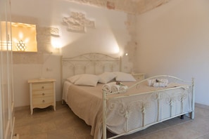 Quarto com cama, mesas de cabeceira e luminária na parede.