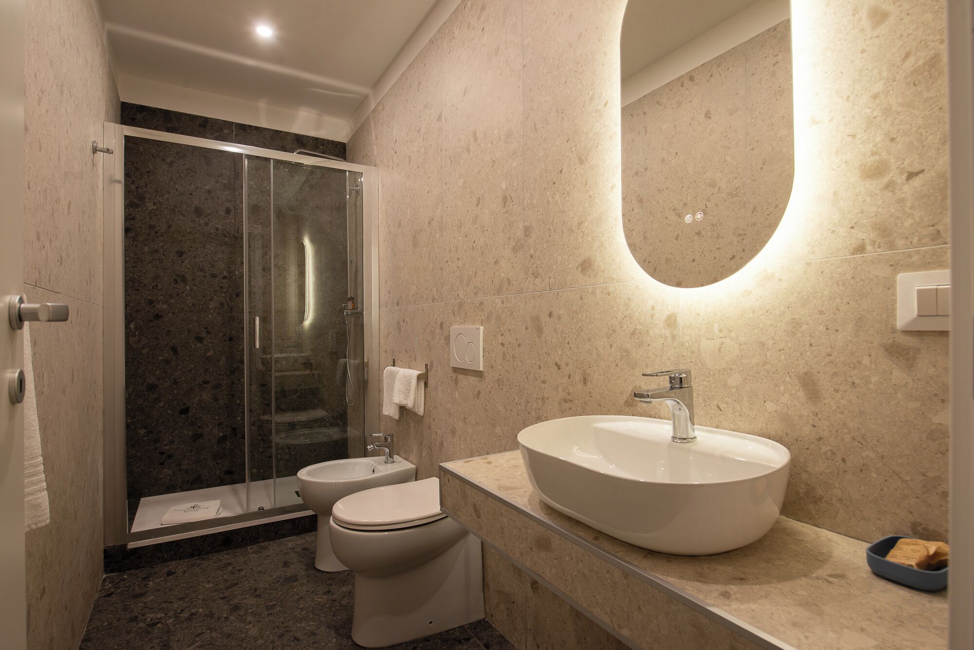 A modern bathroom with a glass-enclosed shower, a toilet, and a large oval sink with a mirror above.