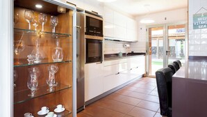 A modern kitchen with glass-fronted cabinets displaying wine glasses and teacups. - Home2Book Coastal Dream Villa in Tacoronte (Tacoronte)