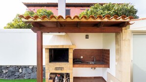 An outdoor kitchen with a brick oven, a sink, and a pergola overhead. - Home2Book Coastal Dream Villa in Tacoronte (Tacoronte)