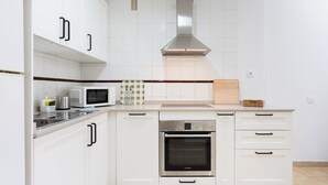 Una cucina moderna con pensili bianchi, un forno Bosch, un microonde e una cappa aspirante in acciaio inossidabile.