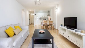 Un soggiorno moderno con divano, tavolino, televisore e zona pranzo.