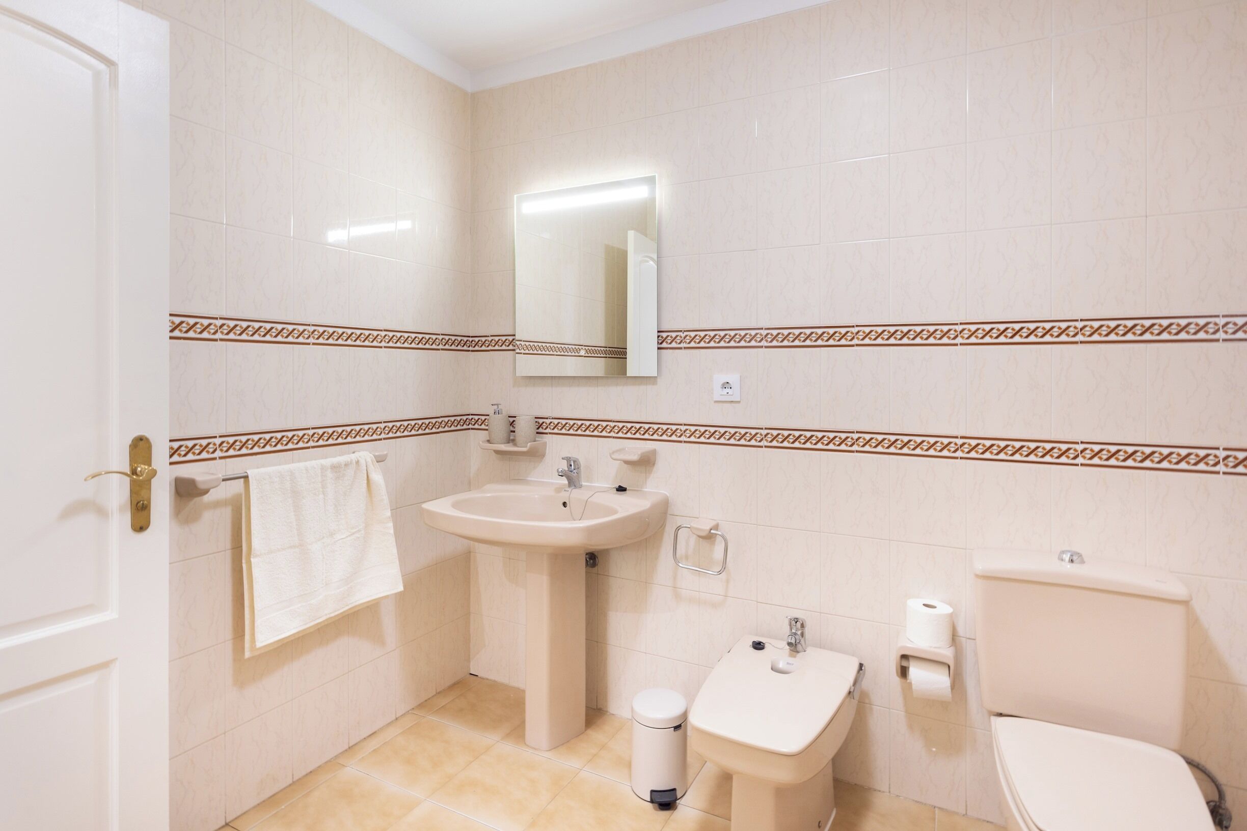 Ein Badezimmer mit Waschbecken, Spiegel, Toilette und Mülleimer.