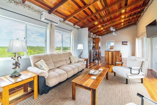 A cozy living room with a wooden ceiling, a sofa, a coffee table, and a TV.