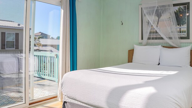 Une chambre avec un lit, une fenêtre donnant sur l’extérieur et un balcon.