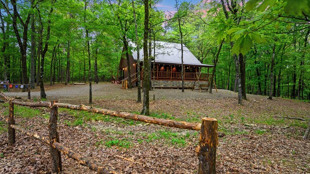 A cabin surrounded by a forest with a gravel path leading to it.