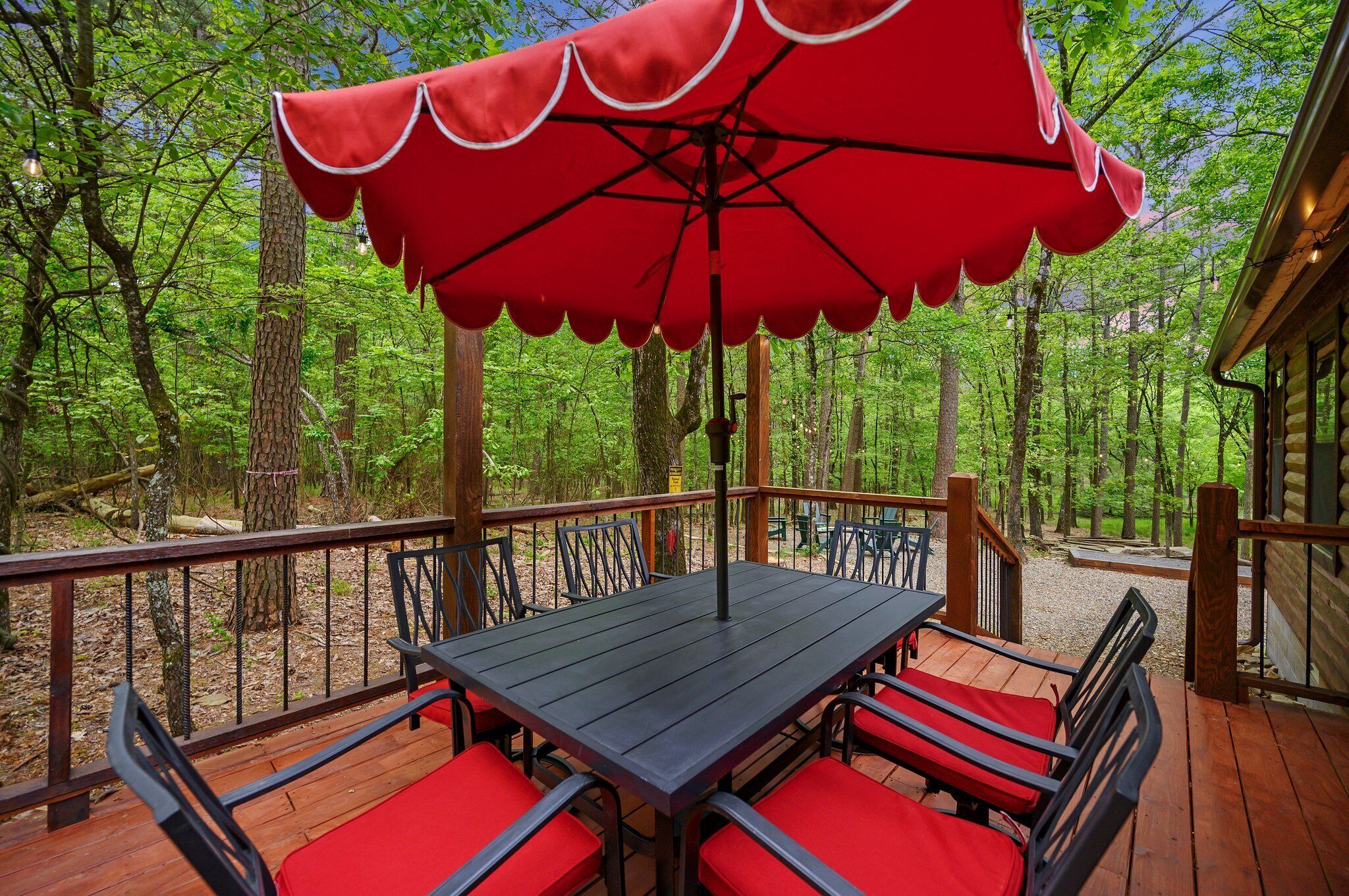 A wooden deck with a table and chairs, surrounded by a forest.