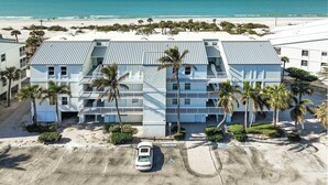 A multi-story hotel with a parking lot, located near a beach.