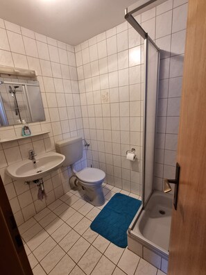 Ett badrum med toalett, handfat och dusch.