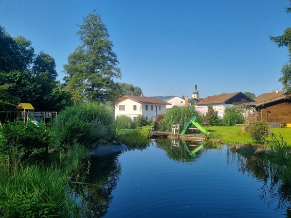 A serene lakeside village with traditional houses, a church steeple, and a clear blue sky.
