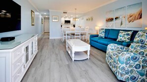 Ein modernes Wohnzimmer mit einem blauen Sofa, einem weißen Couchtisch und einem Fernseher auf einem Schrank.