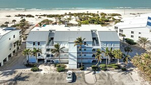 Ein Strandhotel mit mehreren Stockwerken, einem Parkplatz und Palmen.