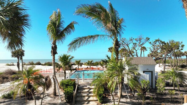 Ein Strandresort mit Pool, Palmen und Blick auf den Ozean.