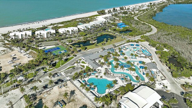 Eine Luftaufnahme eines Resorts mit mehreren Swimmingpools, einem Strand und einer Marina.